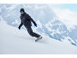 Snowboarder in donkerblauw snowboardpak daalt een besneeuwde berghelling af.