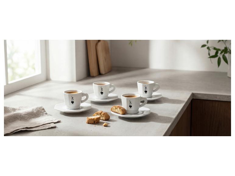 Vier espressokopjes met koekjes op een licht aanrechtblad.
