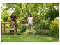 Een vrouw trimt het gras met een PARKSIDE accu-grastrimmer in de tuin naast een man.