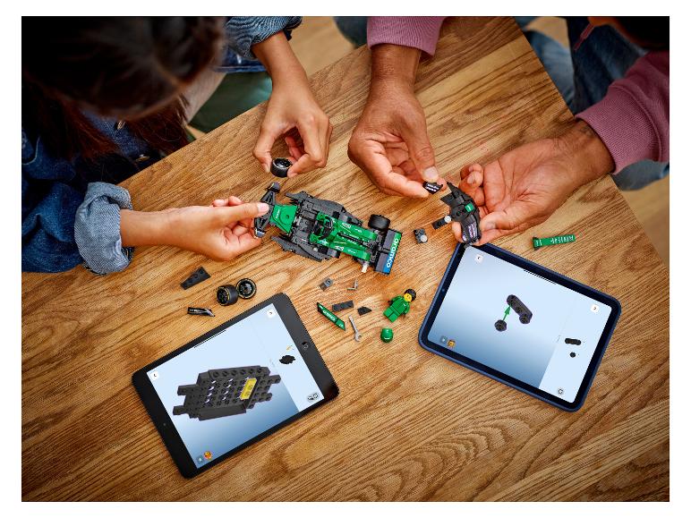Twee mensen bouwen een LEGO raceauto, met instructies op tablets.