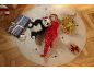 Lachende jongen in rode pyjama ligt op een vloerkleed met knuffels en cadeautjes.