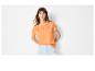 Vrouw in een oranje geborduurd T-shirt en lichte denim shorts.