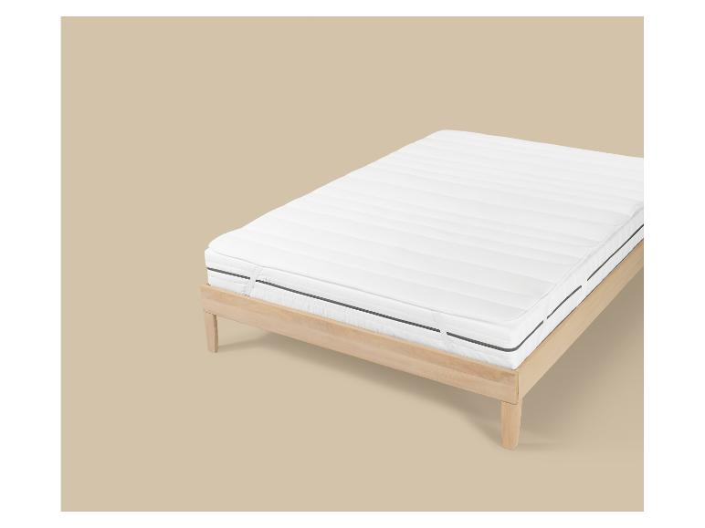 Houten bedframe met wit matras en matrasbeschermer