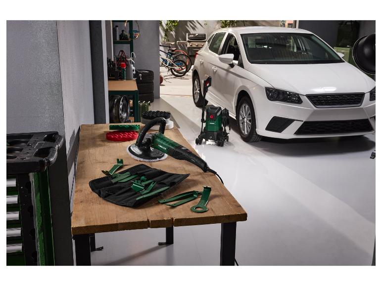 Autopoetsmachine en hogedrukreiniger in een garage met een witte auto.