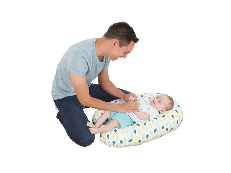 Een vader speelt vrolijk met zijn baby op een kleurrijk kussen.