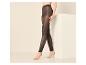 Vrouw draagt doorschijnende zwarte leggings, blootsvoets, staand naast een wit blok.