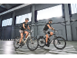 Twee mensen rijden op elektrische fietsen binnen, gekleed in sportkleding.