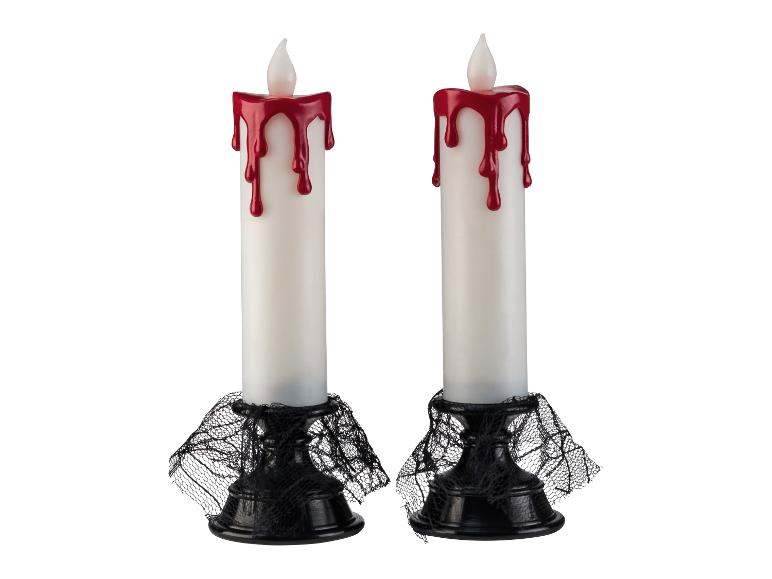 Twee Halloween-kaarsen met rode wasdruppels en zwarte spinnenwebben aan de basis.