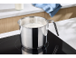 Melk in een roestvrijstalen pan op een kookplaat in de keuken.