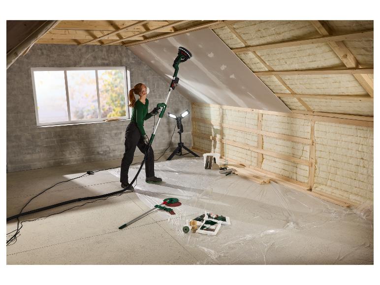Vrouw schuurt het plafond met de PARKSIDE wandschuurmachine op een zolder in renovatie.