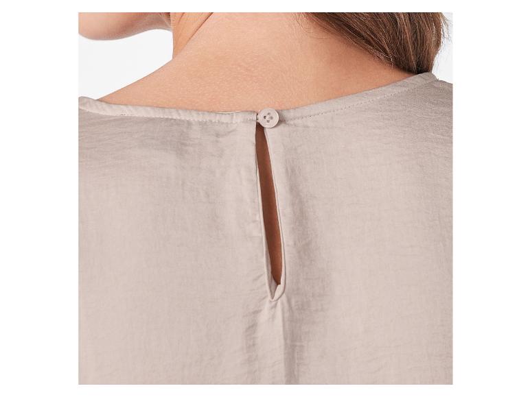 De achterkant van een beige damesblouse met een knoop.