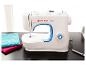 Witte naaimachine met blauwe accenten, met turquoise en roze stof ernaast gevouwen.