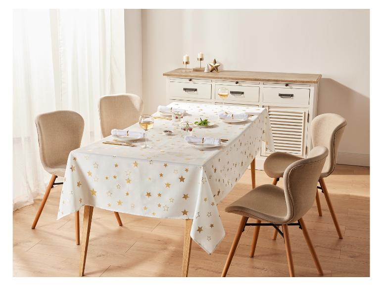 Een witte tafel met gouden sterren, gedekt voor een diner met stoelen