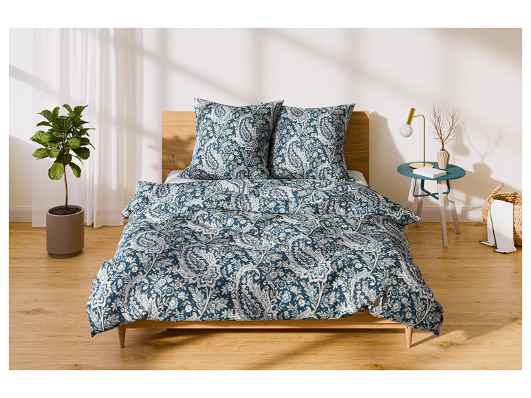 Een bed met een paisley dekbedovertrek en kussens.