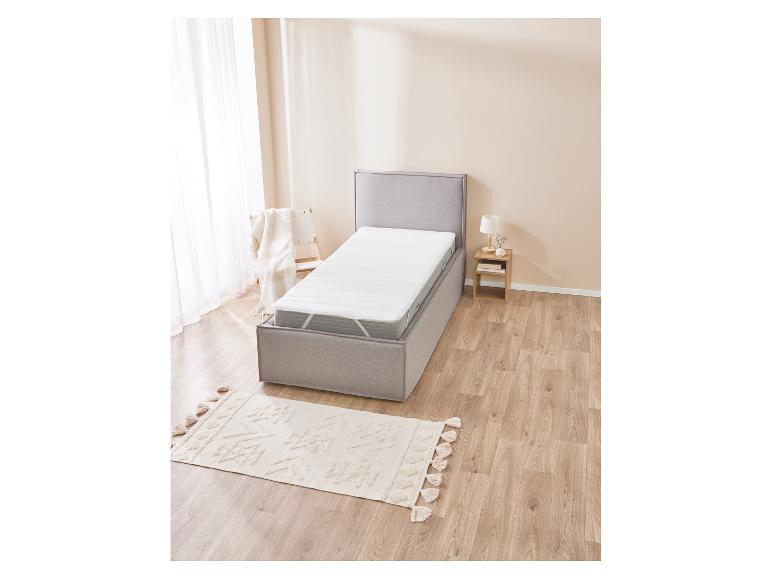 Bed met matras en matrasbeschermer in een moderne slaapkamer.