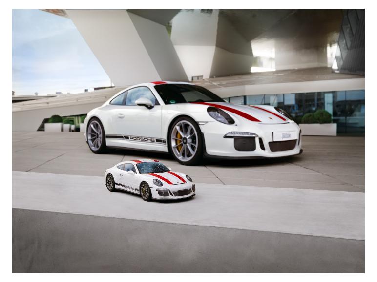 Een witte Porsche 911 GT3 en een kleiner puzzelmodel voor een modern gebouw.