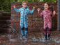 Twee kinderen in regenkleding springen in een plas.