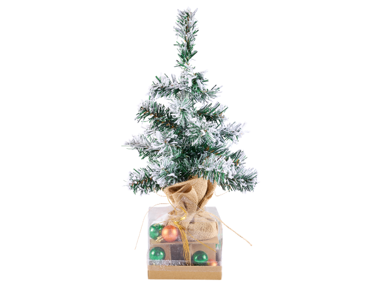 Kleine besneeuwde kerstboom in een decoratieve doos met kerstballen.