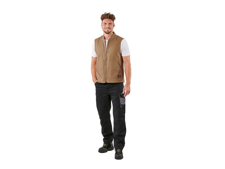 Man in beige bodywarmer en zwarte werkbroek