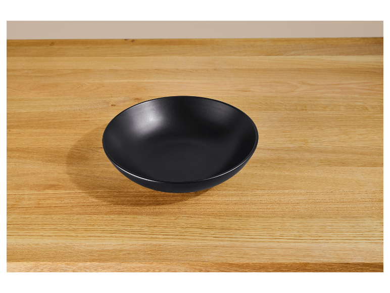 Een zwarte kom op een houten tafel.