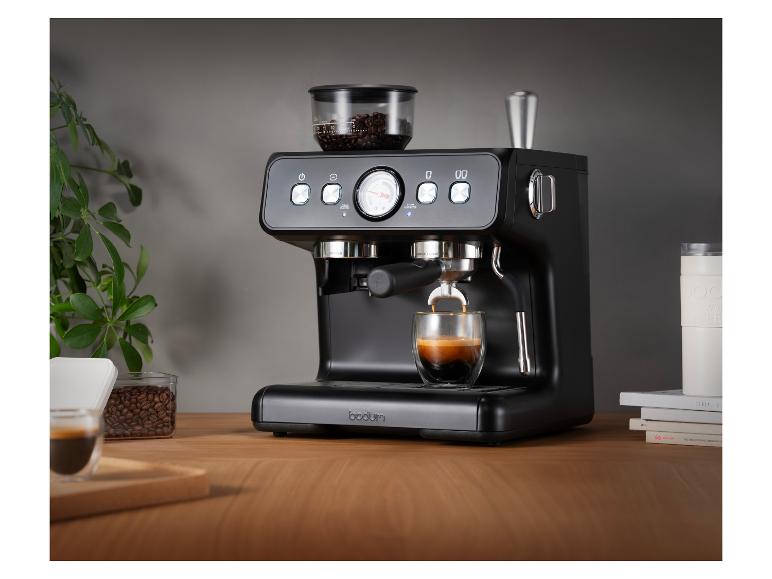 Een zwart Bodum espressomachine zet koffie in een glas op een houten tafel.