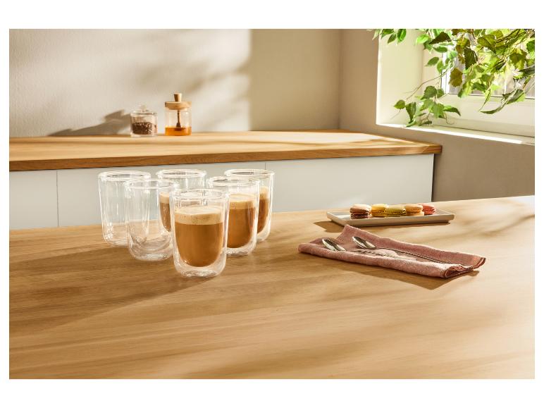 Koffiemokken met koffie en macarons op een houten tafel in de keuken.