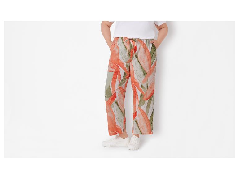 Wijde broek met bloemenprint en witte sneakers.