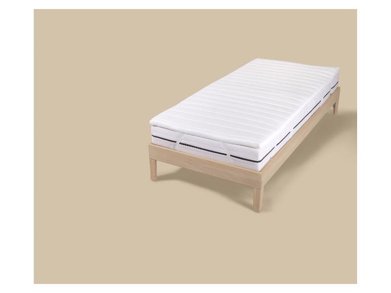 Licht houten eenpersoonsbed met wit matras en topmatras.