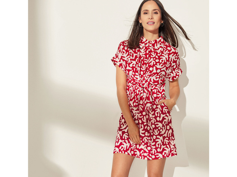 Een vrouw draagt een rode jurk met een abstract patroon.