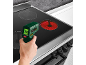Hand houdt een infraroodthermometer vast die de temperatuur van een heet fornuis meet.