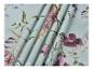 Lichtblauwe stof met een bloemenpatroon van paarse en roze bloemen en groene bladeren.