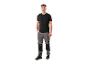 Man in zwart T-shirt en grijze werkbroek met zwarte inzetstukken en werkschoenen.