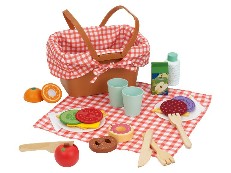 Picknickset met mand, geruite deken, sandwiches, fruit, drankjes en bestek.