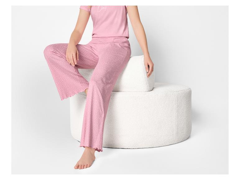 Vrouw in roze pyjama met stippen, zittend op een witte getextureerde kruk.