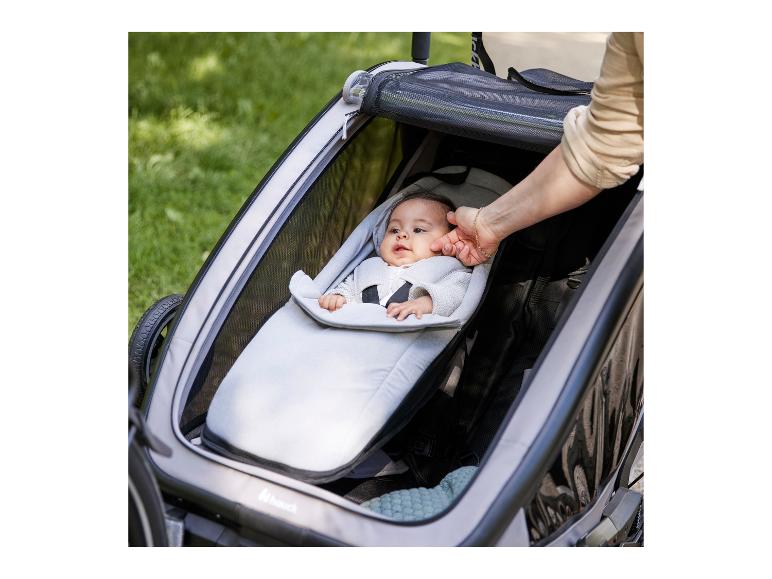 Baby in grijze babydrager in een Hauck fietskar
