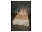 Beige en wit beddengoed met geometrische patronen op een bed met nachtkastje en lamp.