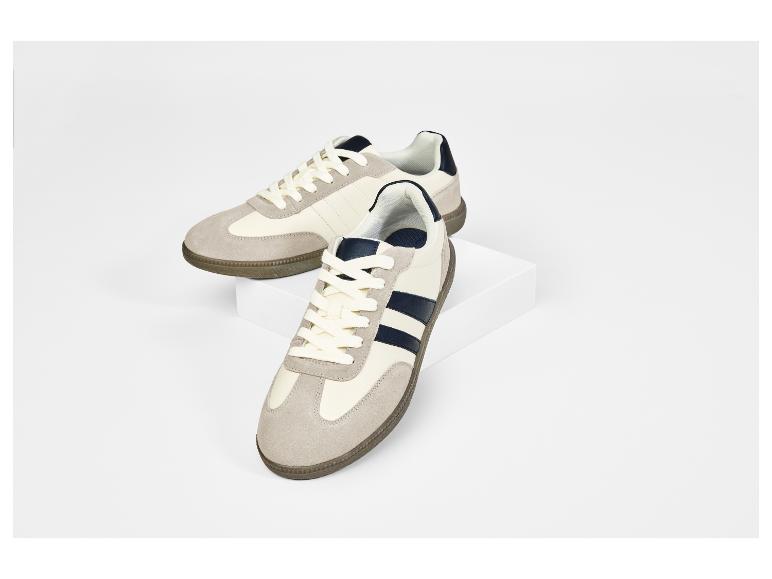 Twee beige en marineblauwe sneakers op een witte achtergrond.