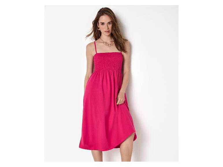 Vrouw in roze mouwloze jurk met gouden sieraden