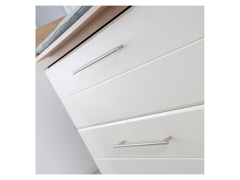 Witte commode met drie laden en zilveren handgrepen.