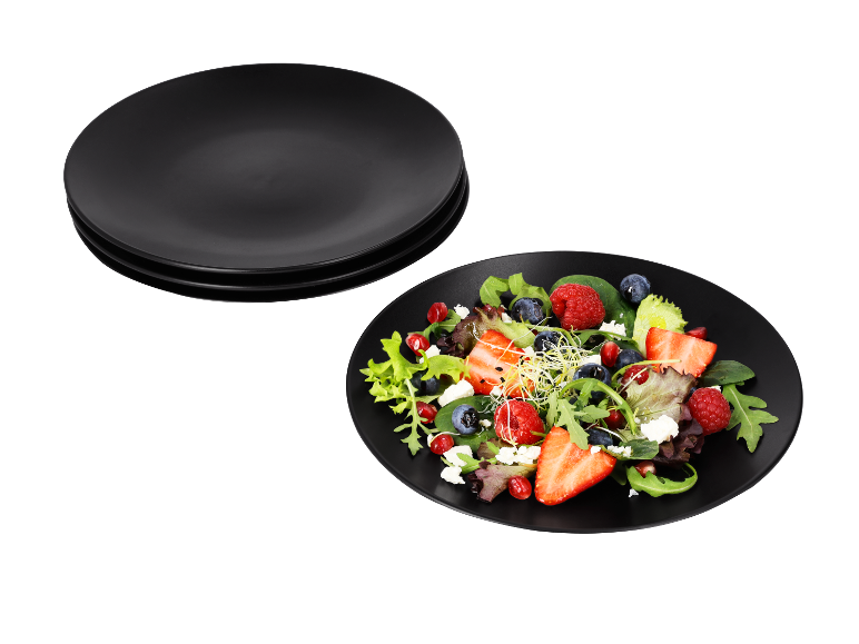 Rode fruitsalade met feta op een zwart bord.