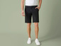 Een man draagt ​​zwarte chino shorts en witte sneakers.