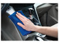 Een hand die een blauwe microfiberdoek gebruikt om het dashboard van een auto schoon te maken.