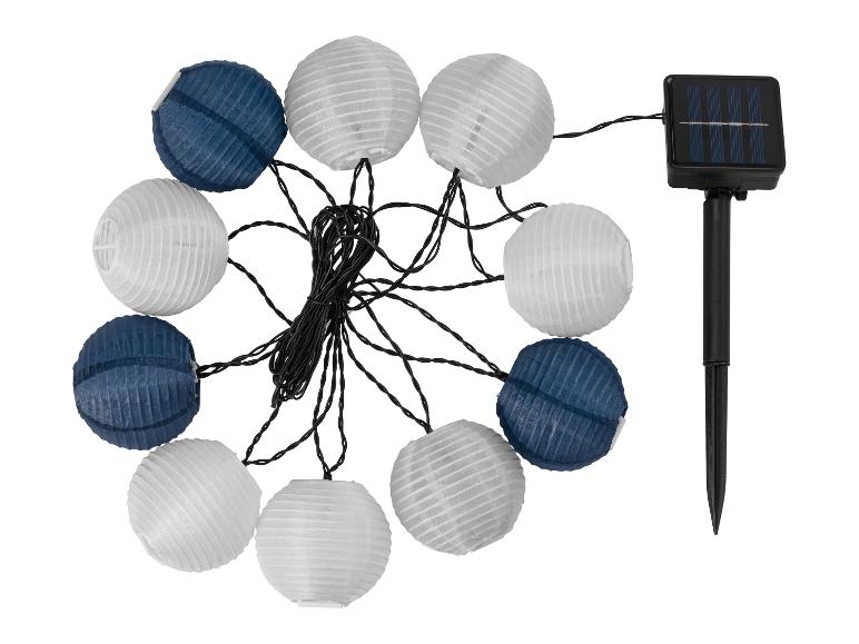 Op zonne-energie werkende lichtslinger met witte en blauwe papieren lantaarns en zonnepaneel.