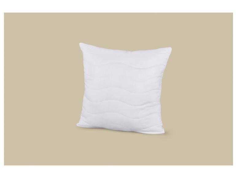 Wit kussen met een golvend patroon op een beige achtergrond