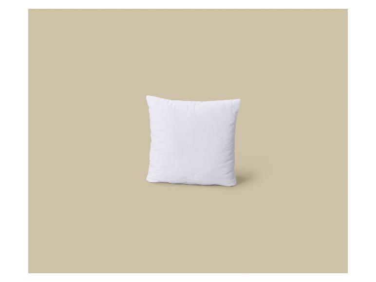 Wit gewatteerd kussen op een beige achtergrond.