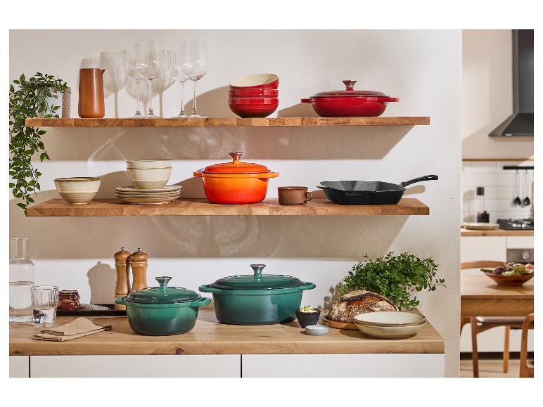 Le Creuset pannen en potten op houten planken in een stijlvolle keuken.