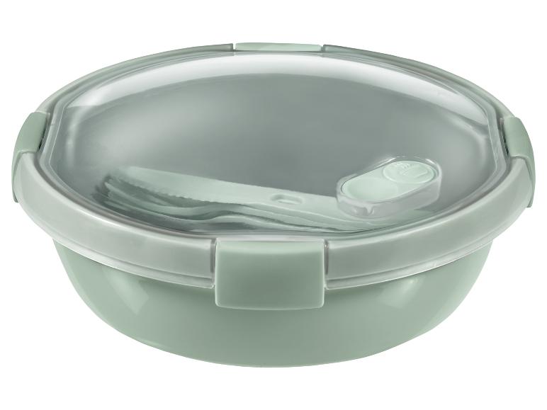 Een groene lunchbox met een transparant deksel en bestek.