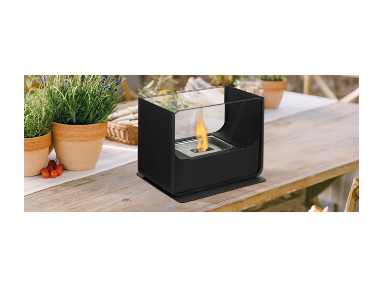 Een zwart bio-ethanol haardvuur op een houten tafel.