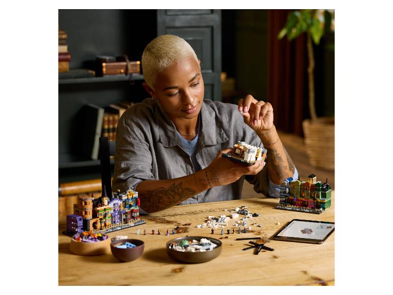 Een vrouw assembleert een LEGO set, met andere LEGO modellen op tafel.