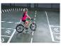 Vrouw met helm en reflecterend vest rijdt op een elektrische fiets op een baan met witte lijnen en pijlen.